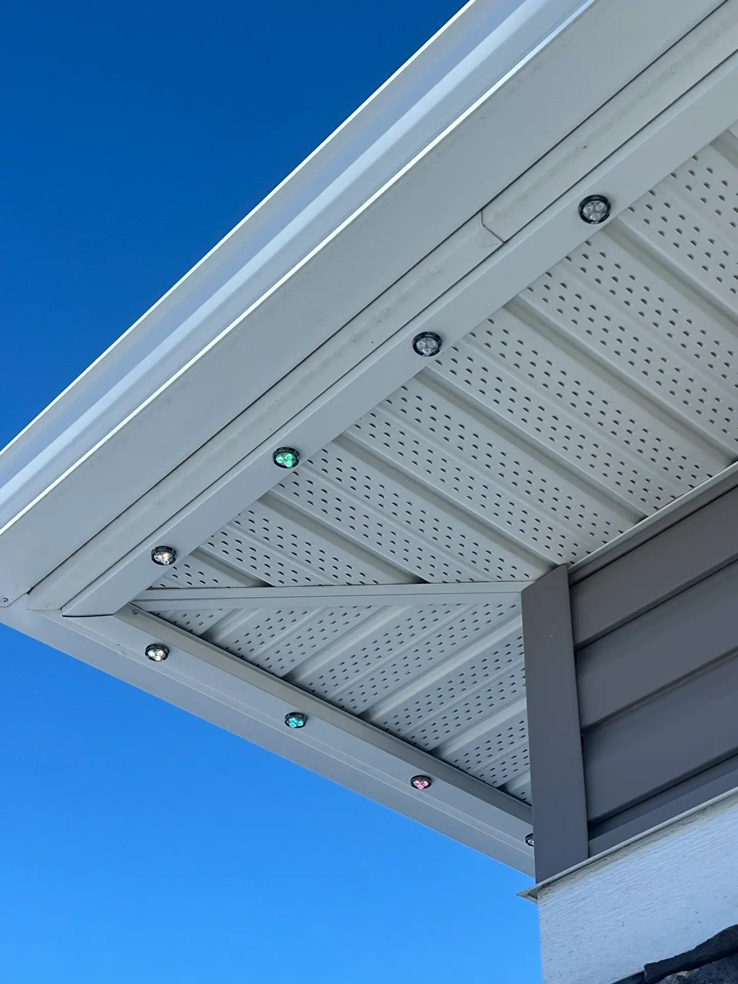 Close-up of the aluminum track and multicolour puck lights under a soffit in daylight